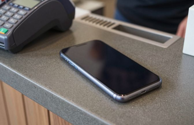 A smartphone lying face up on a cafe counter beside a card payment terminal